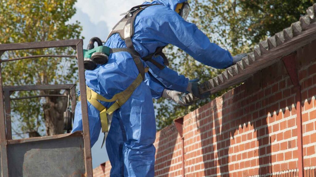 A worker in protective gear removes mold from a rooftop