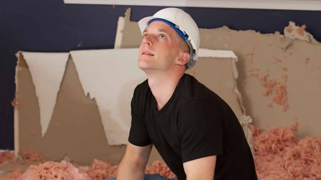 Contractor inspecting water-damaged drywall for repairs