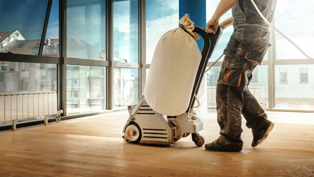 Worker sanding hardwood floors in a commercial building