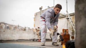 Worker using a blowtorch to apply a waterproofing membrane on a rooftop