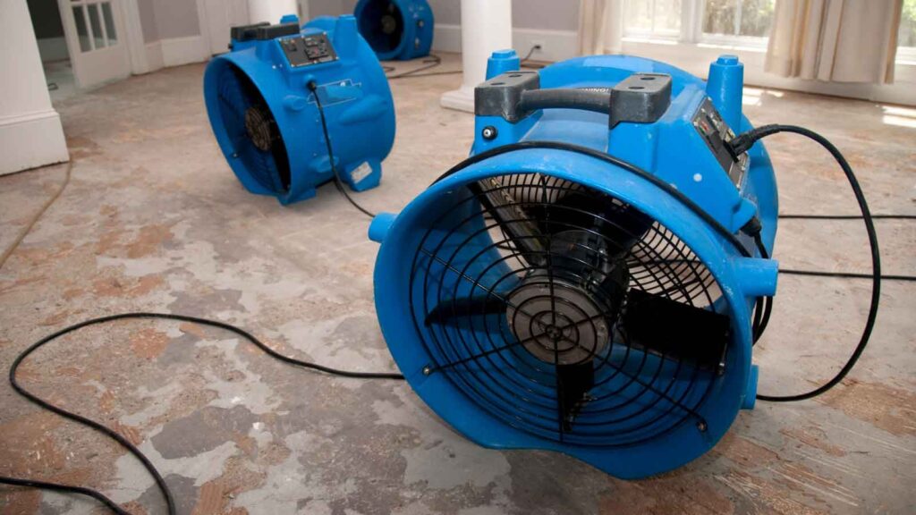 Industrial air movers dry a water-damaged floor.