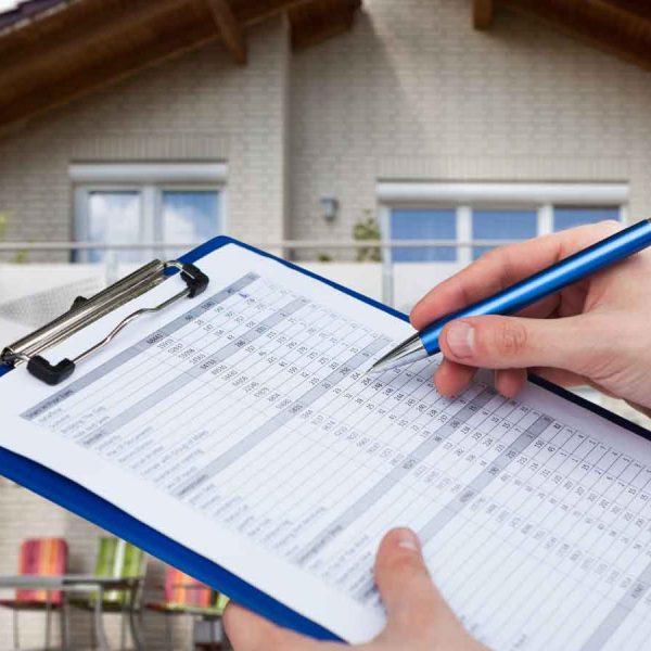 Inspector filling out a property assessment checklist in front of a house