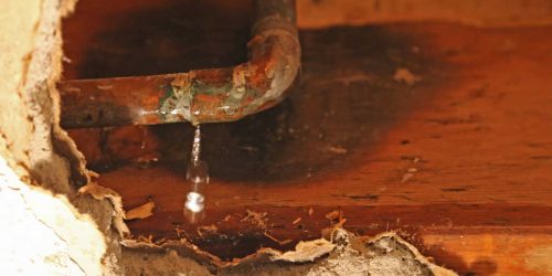 Leaking corroded pipe causing water damage to the surrounding area.