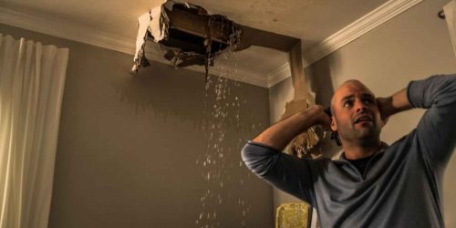 Man reacts to ceiling collapse and heavy water leakage indoors.