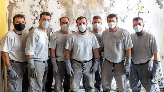 Mold remediation team wearing protective gear standing in front of a treated wall