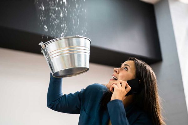 Woman catching water in a bucket while calling for help