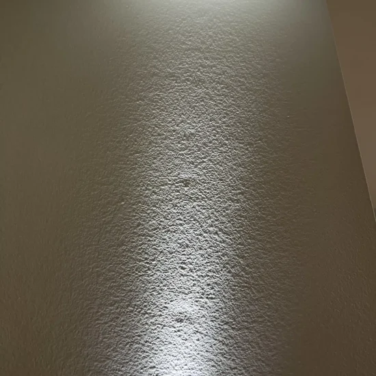 Textured wall surface inspection revealing moisture damage patterns during mold remediation process