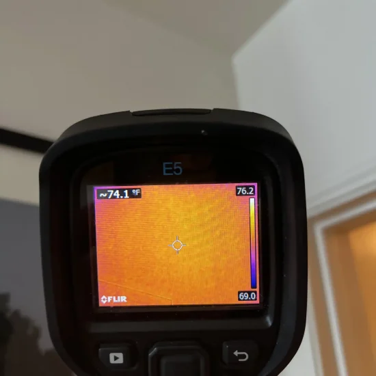 FLIR thermal camera showing 74.1°F reading in corner area during professional moisture assessment